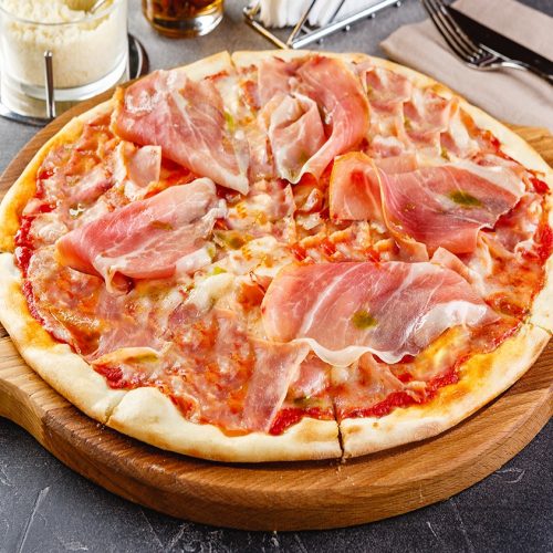 Pizza with salami and prosciutto on wooden board on dark background